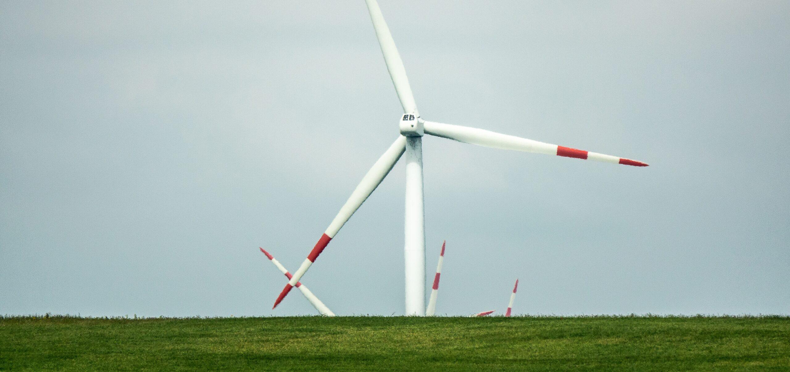 A wind fan standing on a green landscape during daytime